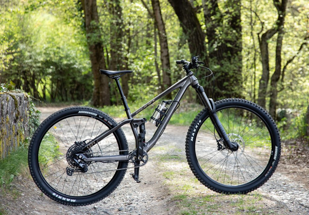 VTT a axe traversant 148mm équipé d'un kit d'électrification roue arrière ANNAD sur fond de forêt.